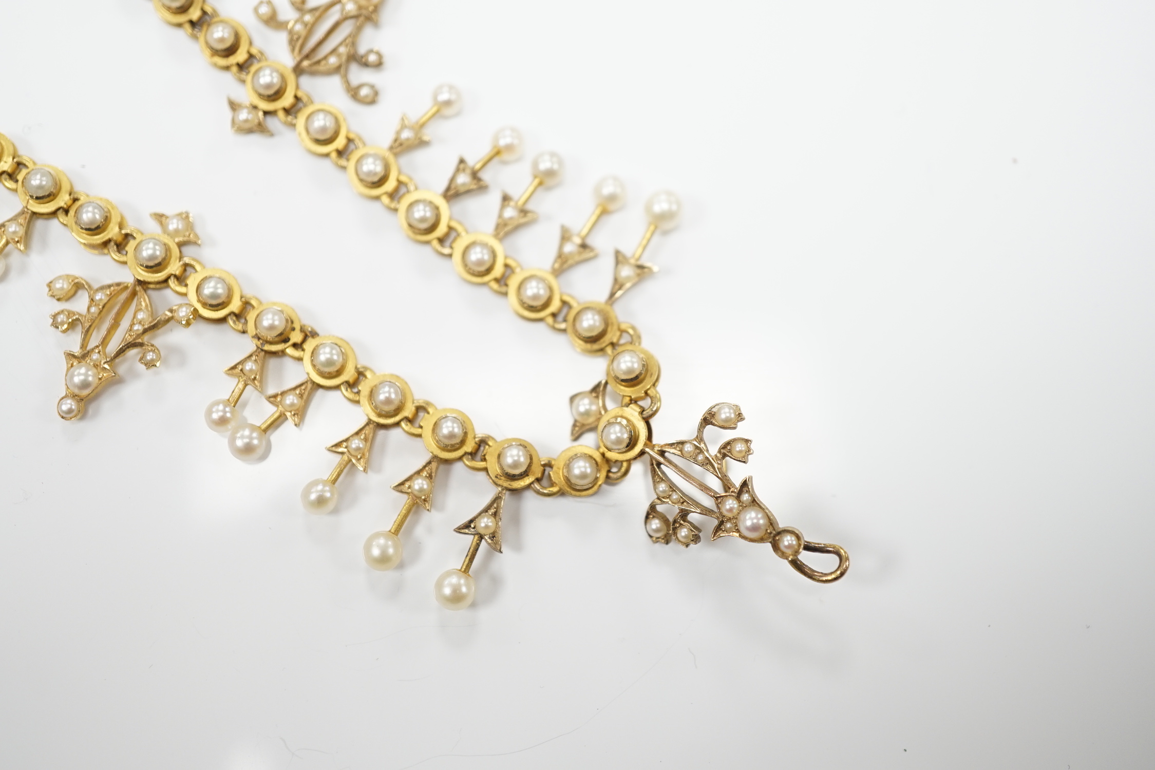 An Edwardian yellow metal and seed pearl set necklace, lacking drops and clasp, 39cm, gross weight 26.2 grams.